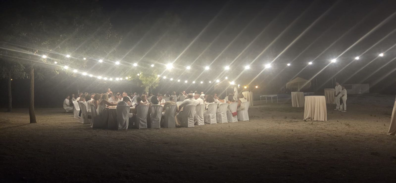 Cena al aire libre en El Colorao: mesas con las sillas vestidas de blanco bajo guirnaldas de luces