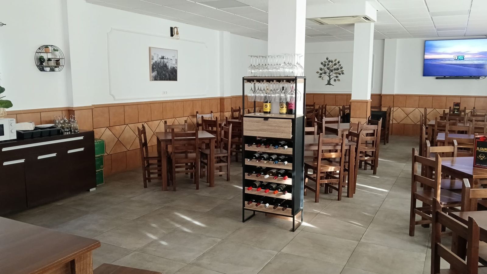 Salón de El Colorao con mesas de madera, botellero y aire acondicionado